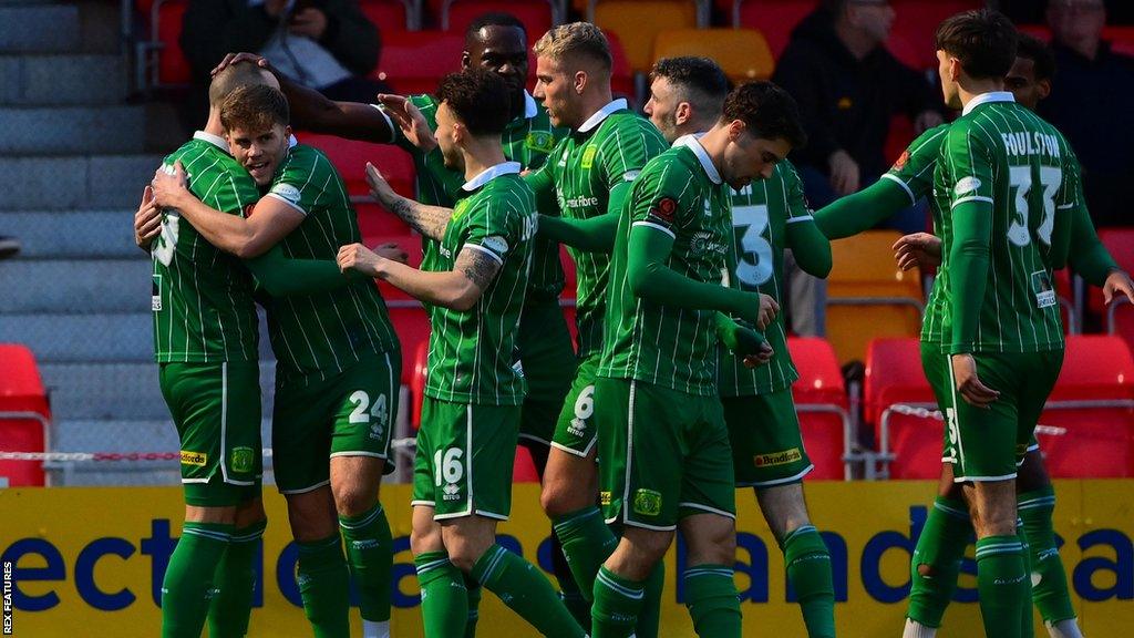 Yeovil Town players hug in celebration of a goal against Truro City