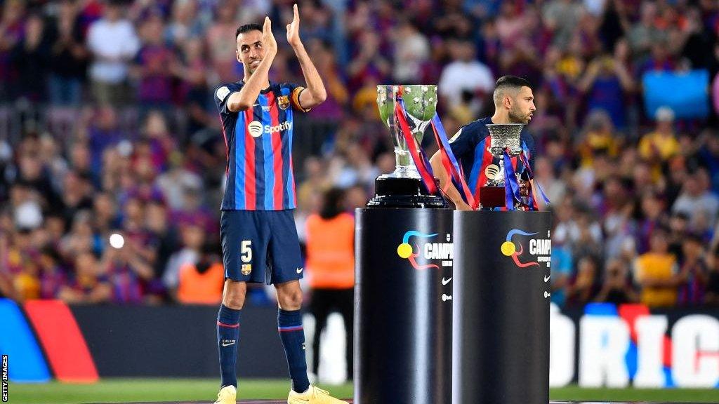 Sergio Busquets and Jordi Alba stand near the La Liga and Spanish Super Cup trophies at the end of Barcelona's La Liga win over Mallorca