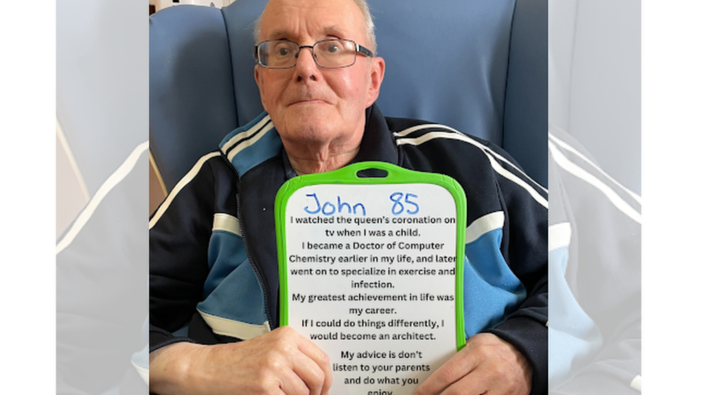 John wearing glasses and holding up his personal message.