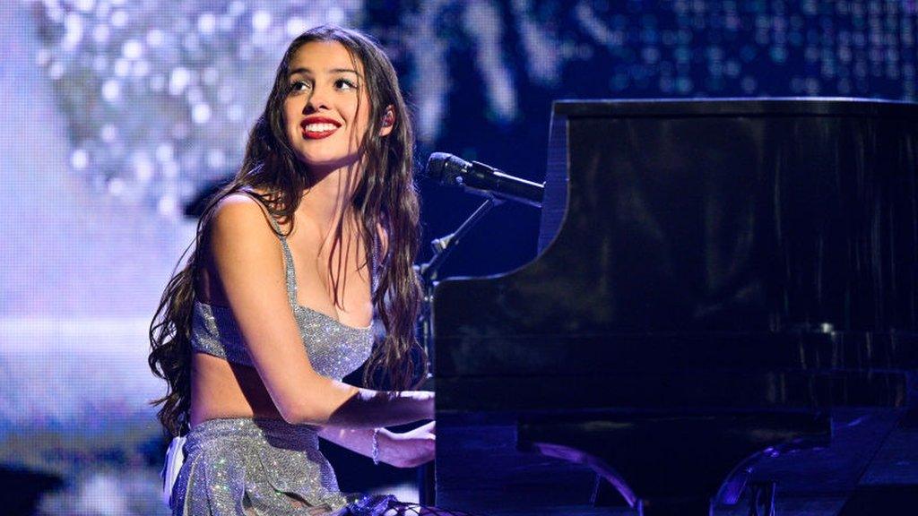 Rodrigo smiles at the crowd as she plays piano on stage