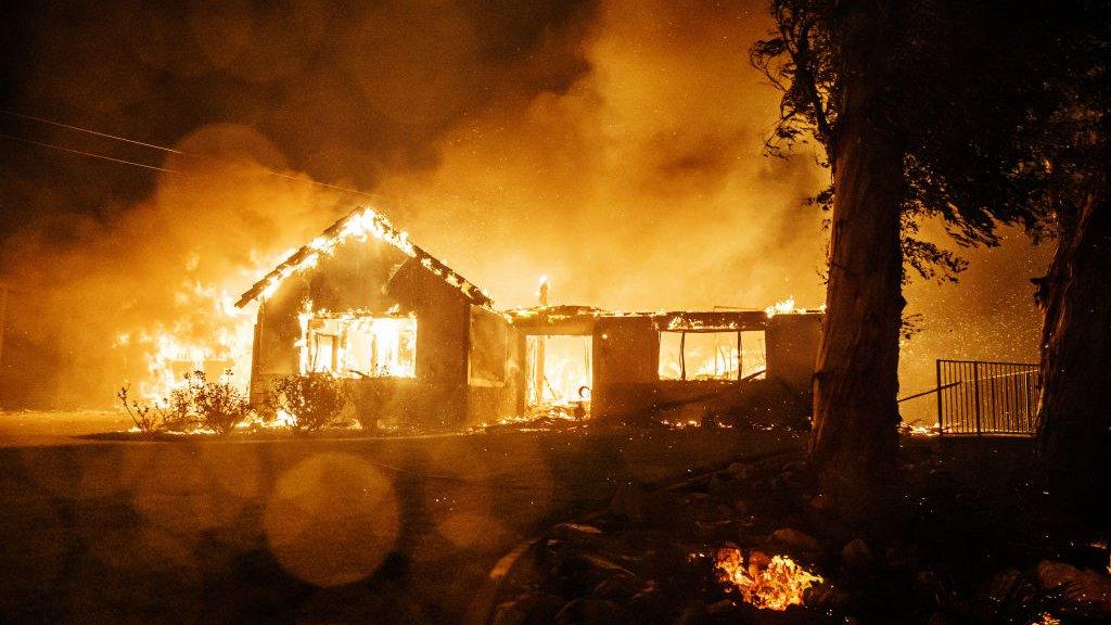 A home burns after winds push the Hillside fire down a hill to engulf homes in San Bernardino