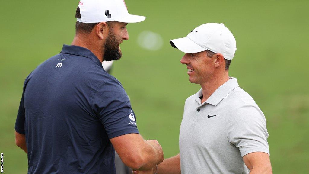 Jon Rahm and Rory McIlroy shake hands on the range at the Masters