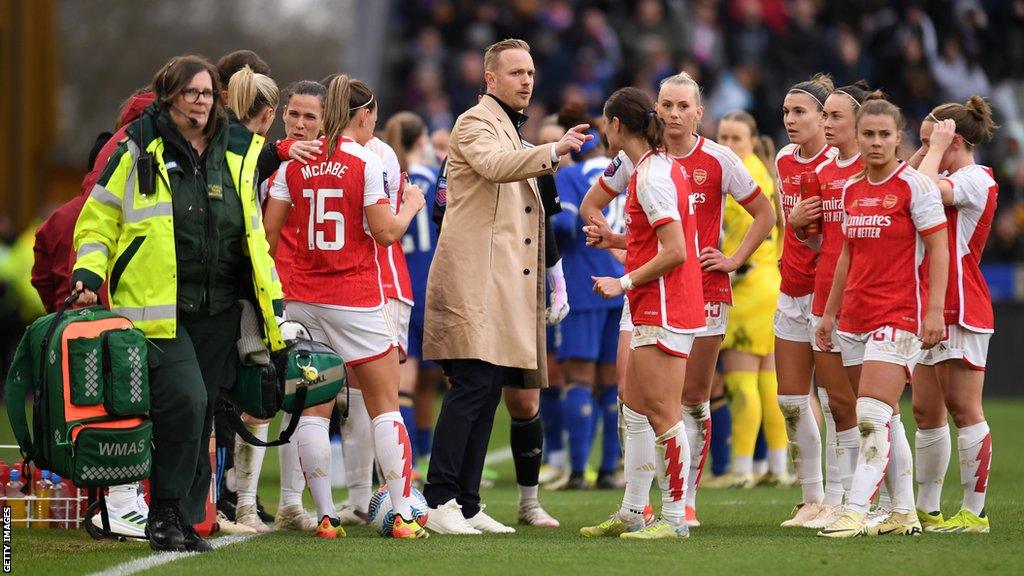 Jonas Eidevall, manager of Arsenal, talks to the team as Frida Maanum of Arsenal receives medical treatment