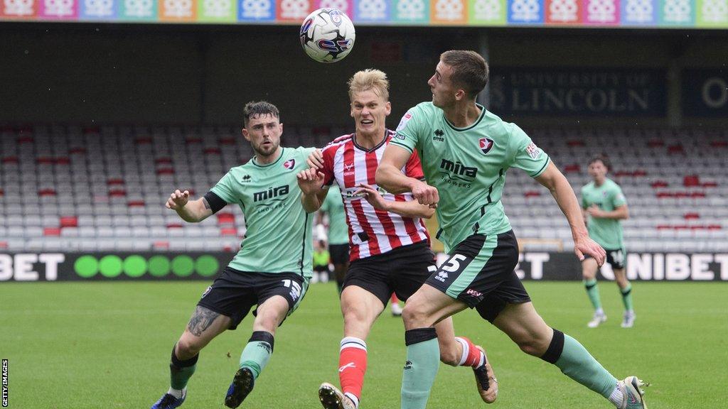 Cheltenham's Will Ferry and Owen Bevan challenge Lincoln's Lasse Sorensen for the ball during their game