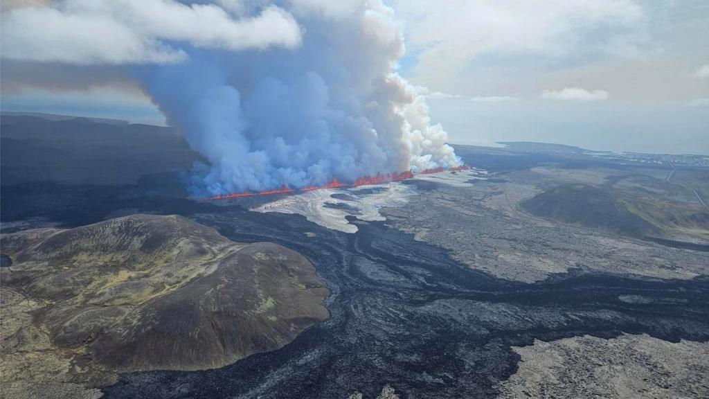 Aerial photo of a fissure of magma after a volcanic eruption, you can see a massive plume of ash and glowing molten rock