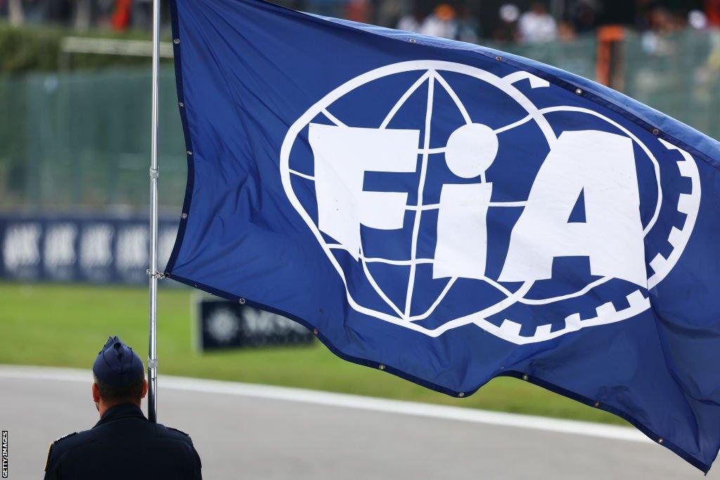 A man holding a flag with the FIA logo on