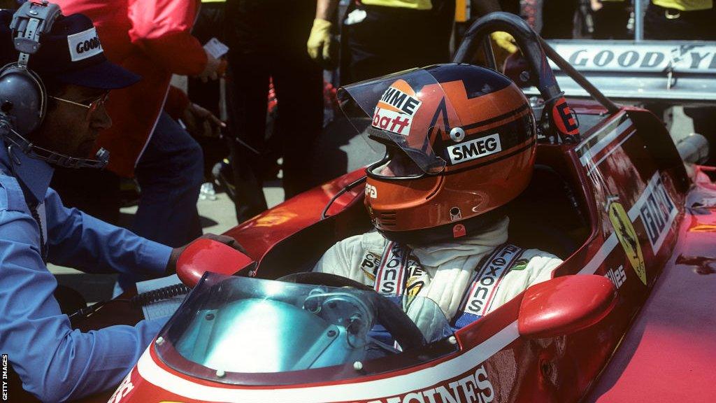 Gilles Villeneuve talks with an engineer while in the cockpit of his Ferrari