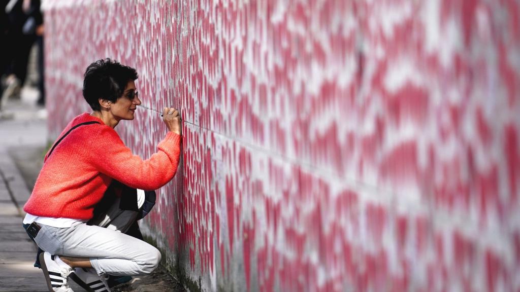 A woman writes on the Covid memorial wall