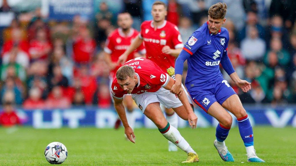 Wrexham forward Sam Dalby is challenged by MK Dons' Ethan Robson