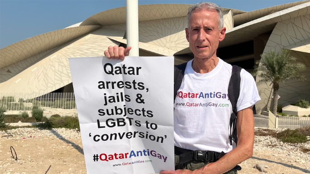 Peter Tatchell holds placard reading "Qatar arrests, jails & subjects LGBTs to conversion", with the hashtag "#QatarAntiGay".