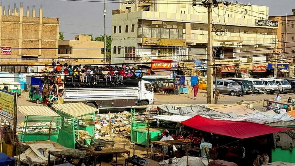 People gather to ride a truck to flee outside Khartoum,