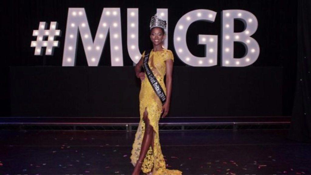 The first black Miss Universe GB, Dee-Ann Kentish-Rogers poses on stage.