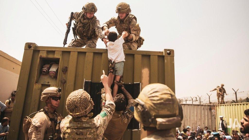 UK coalition forces, Turkish coalition forces, and US Marines assist a child