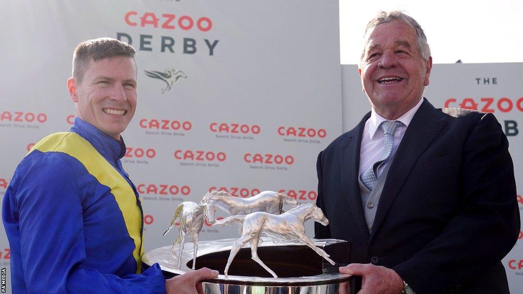 Jockey Richard Kingscote and trainer Sir Michael Stoute with the trophy after winning the Cazoo Derby with Desert Crown on Derby Day during the Cazoo Derby Festival 2022 at Epsom