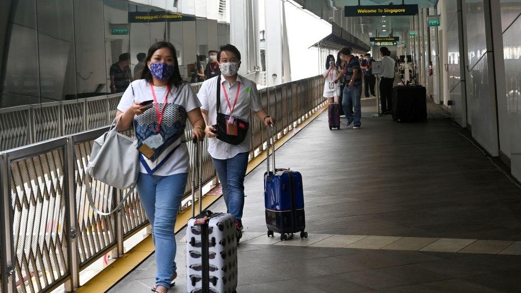 Passengers walk toward the World Dream cruise ship docked at Marina Bay Cruise Centre before its departure to "cruises to nowhere" in Singapore on November 6, 2020 in a bid to revive its pandemic-hit tourism industry.