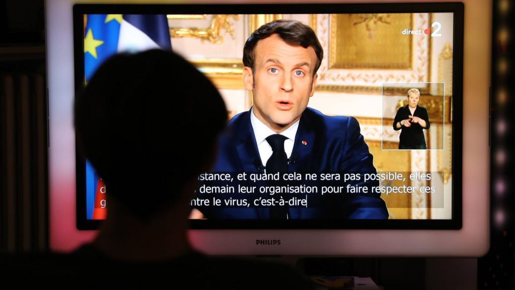 French President Emmanuel Macron is seen on a television screen as he speaks during a televised address to the nation on the outbreak of COVID-19, caused by the novel coronavirus, on March 16, 2020, in Paris.