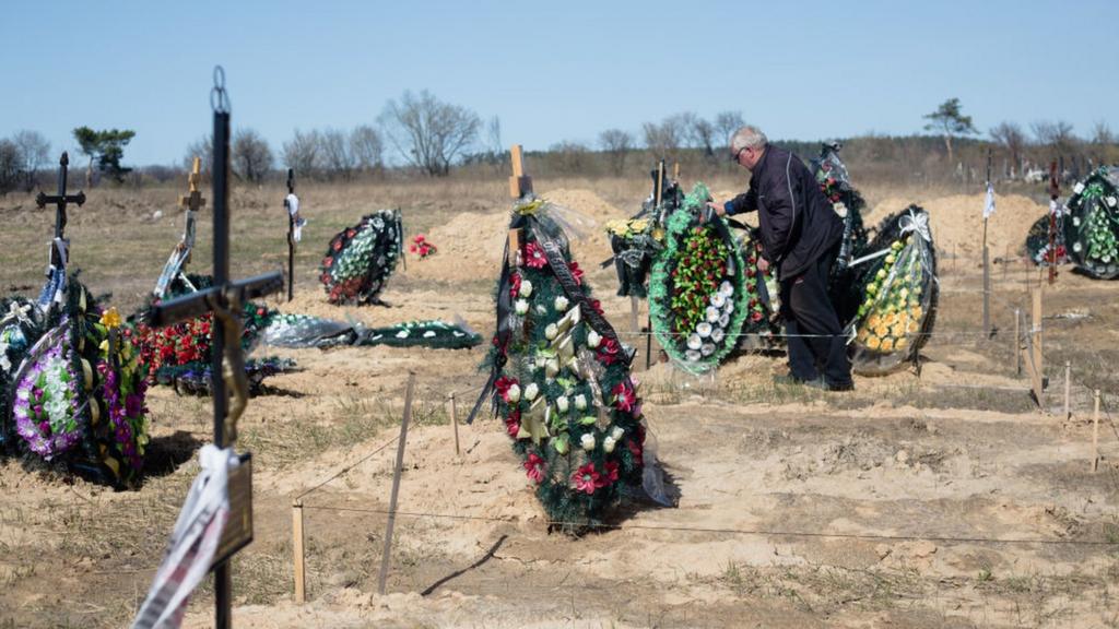 A man fixes the wreath on the grave in a cemetery on April 14, 2022 in Hostomel, Ukraine