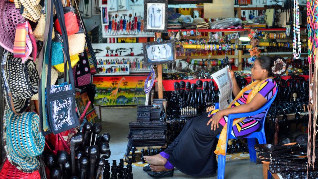 A woman reading a newspaper at a market stall in Zanzibar, Tanzania