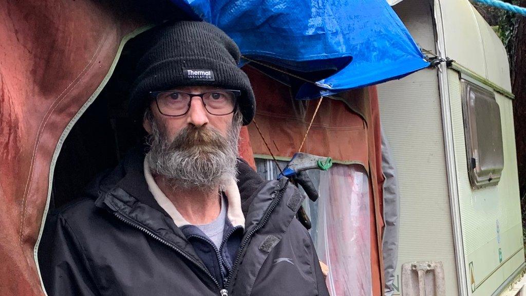 Man stood in front of a caravan