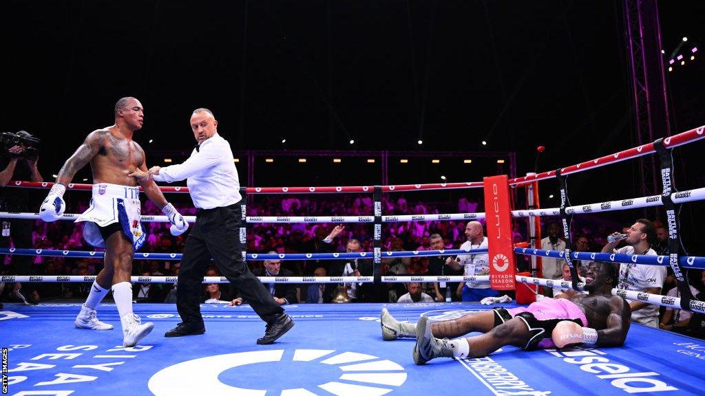 Fabio Wardley is pushed back by referee John Latham as David Adeleye lies on the floor