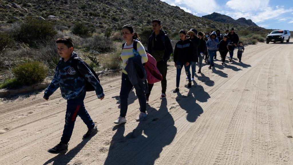 Migrants walk on a dirt road after crossing the nearby border with Mexico near the Jacumba Hot Springs on February 23, 2024 in San Diego, California.