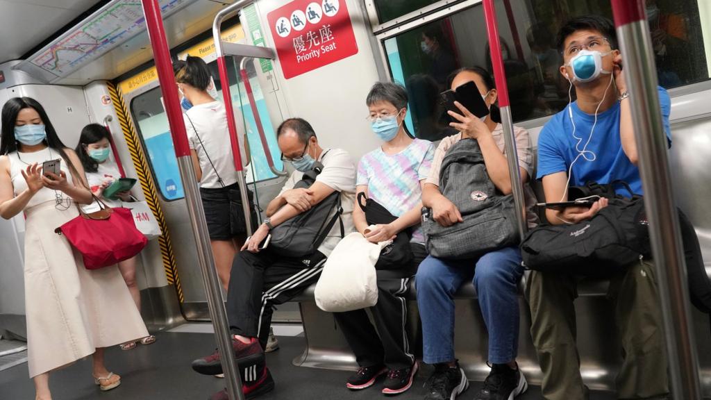 People wearing face masks ride a subway train amid the coronavirus outbreak