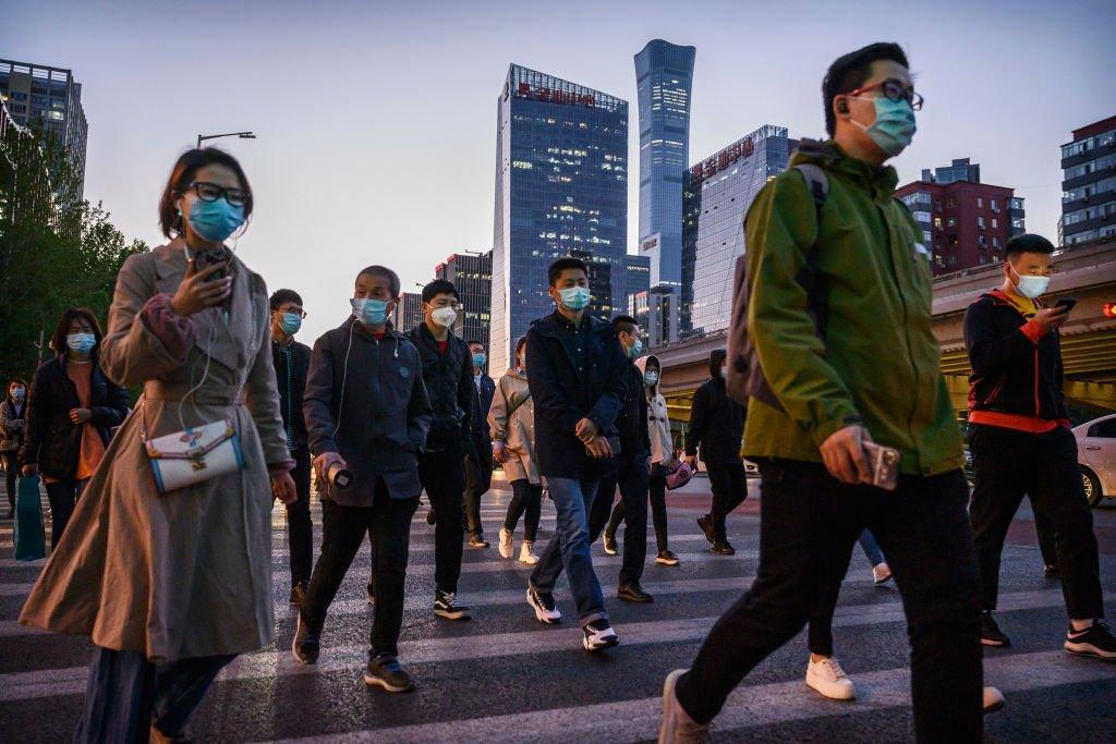 Commuters cross an intersection during rush hour in Beijing.