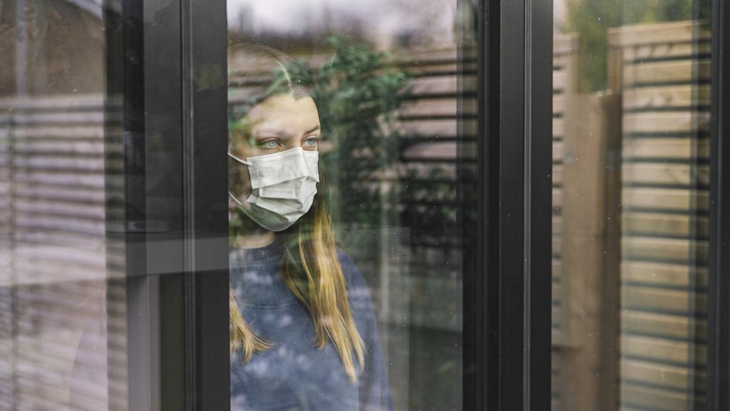 A woman wearing a mask works at her desk