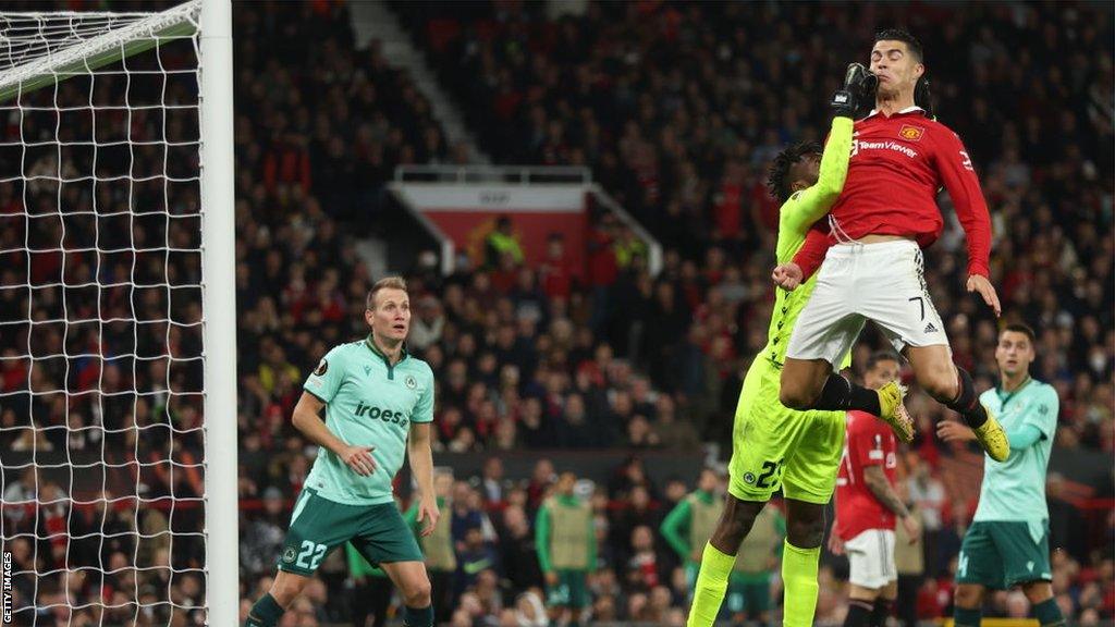 Omonia Nicosia keeper Francis Uzoho jumps to punch a ball away as Manchester United's Cristiano Ronaldo tries to head it