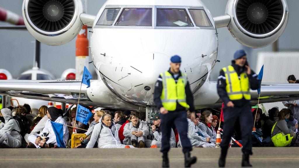 Demonstrators sitting under a private jet at Schiphol Airport on 5 November