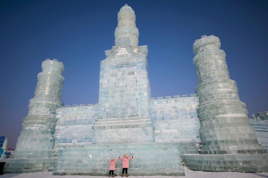 two kids in front of giant ice castle structure