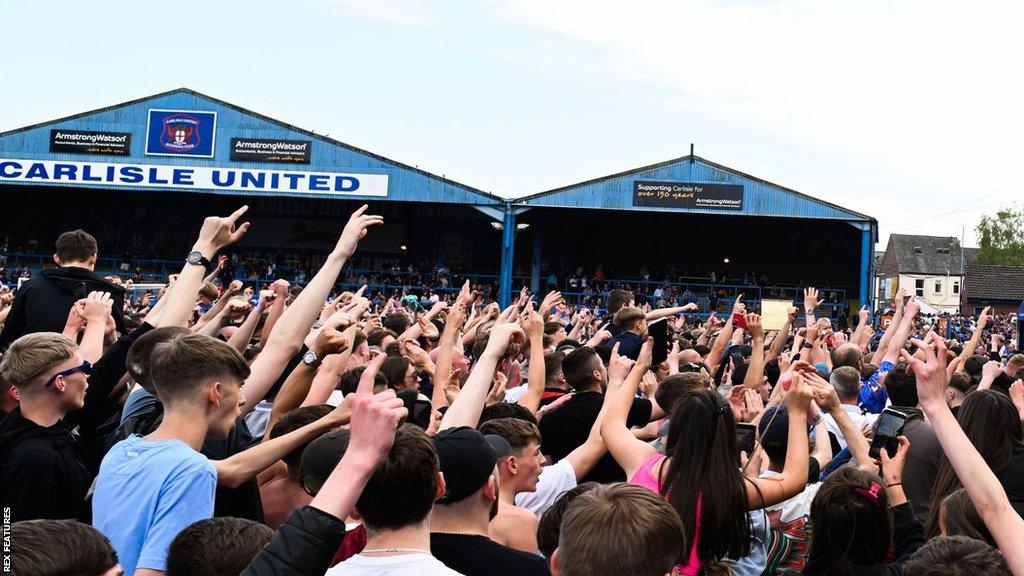 Carlisle United fans on the pitch at Brunton Park after the semi-final