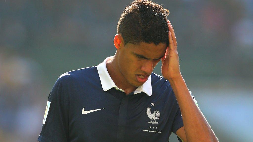 Raphael Varane playing for France with his hand held up to his head