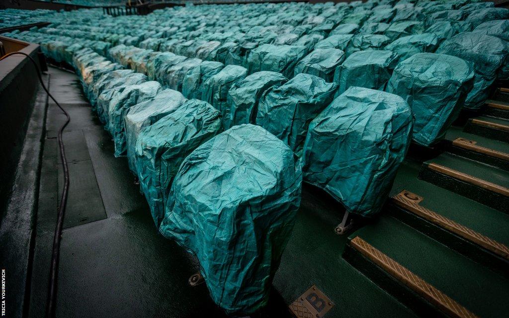 Centre Court seats covered in seat covers on a damp day at Wimbledon