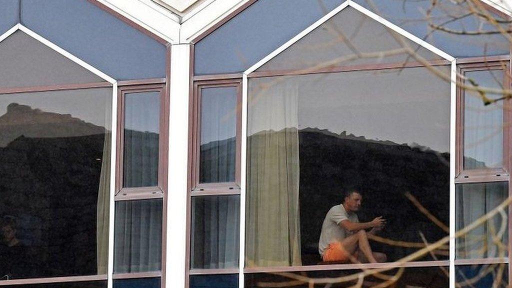 A man sits at a window of the Radisson Blu hotel at Heathrow Airport in west London