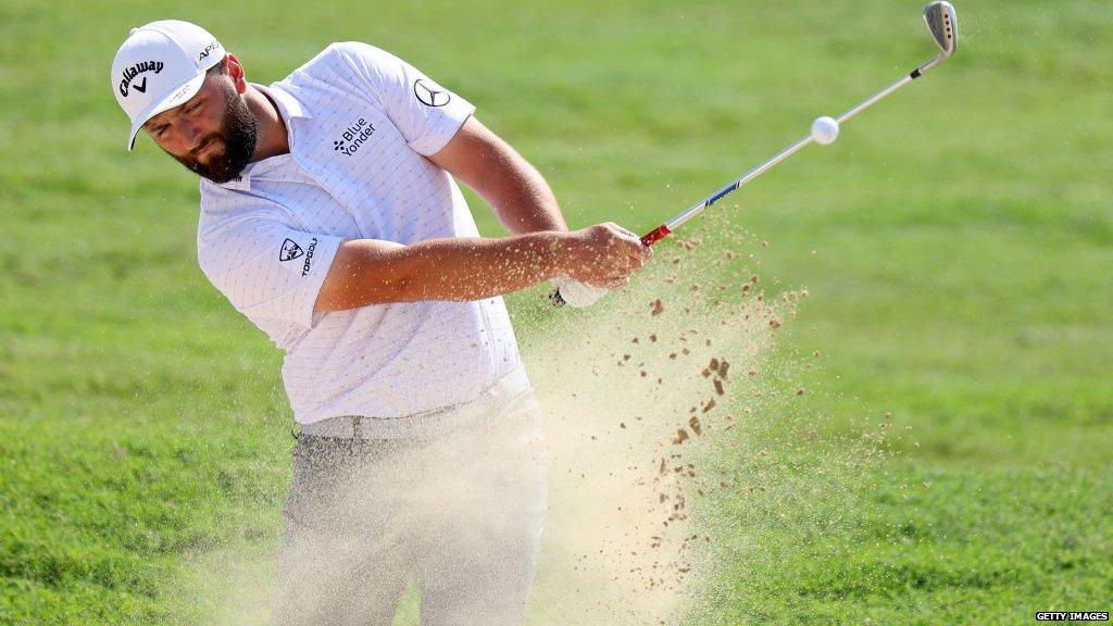 Jon Rahm hitting a shot out of a bunker