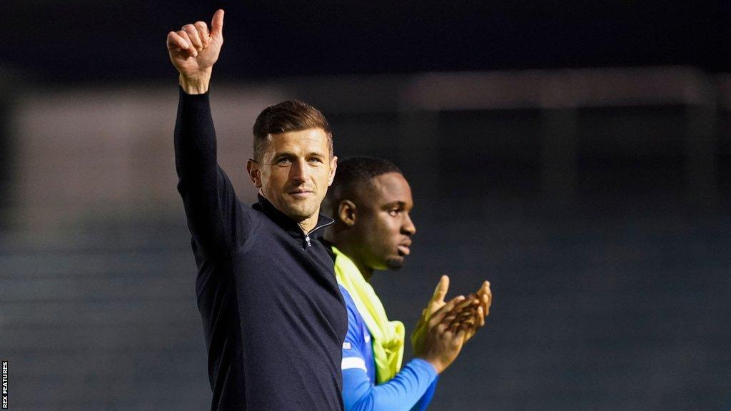 Portsmouth boss John Mousinho gives a thumbs up to the crowd as his side leave the pitch following a League One game.