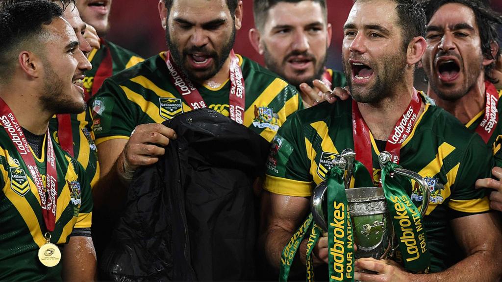 Cameron Smith (C) holds the trophy