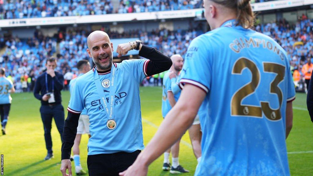 Manager Pep Guardiola celebrates on the pitch after leading Manchester City to another trophy