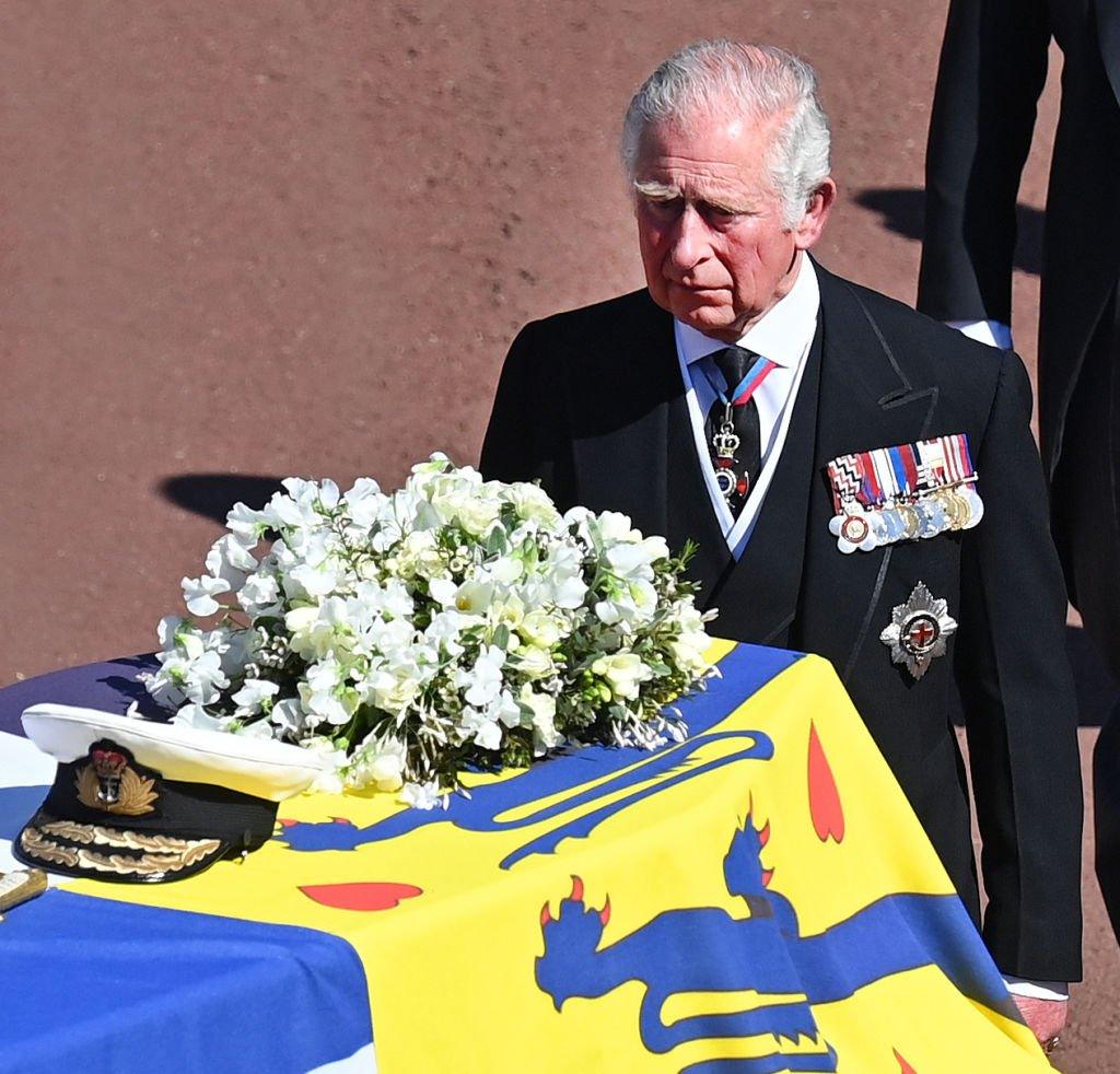 In 2021 the King's father Prince Philip, the Duke of Edinburgh died. Here King Charles can be seen following the coffin (draped in Prince Phillip's Royal Standard Flag and bearing his Royal Navy cap, sword and a bouquet of lilies and white roses) as it is carried on a specially designed Land Rover during his funeral procession to St. George's Chapel at Windsor Castle.