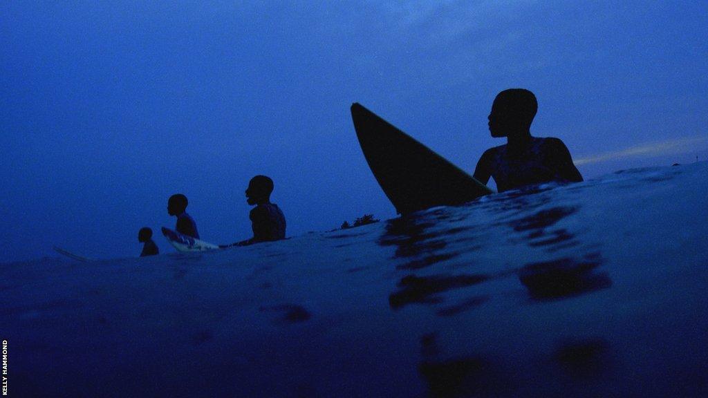 A group of surfers wait for a wave off the coast of Busua in Ghana