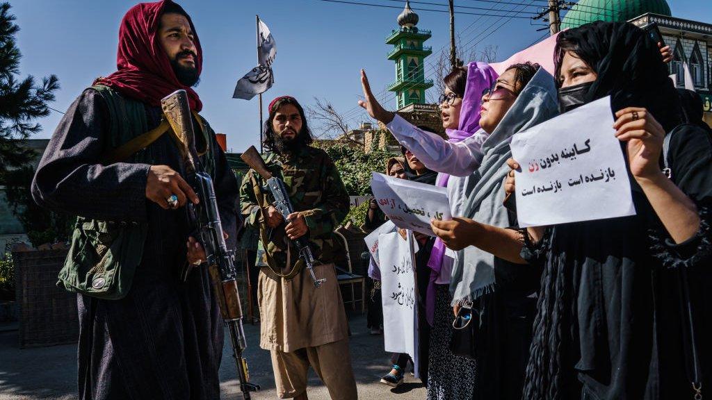 A Taliban fighter stares at demonstrators in Kabul