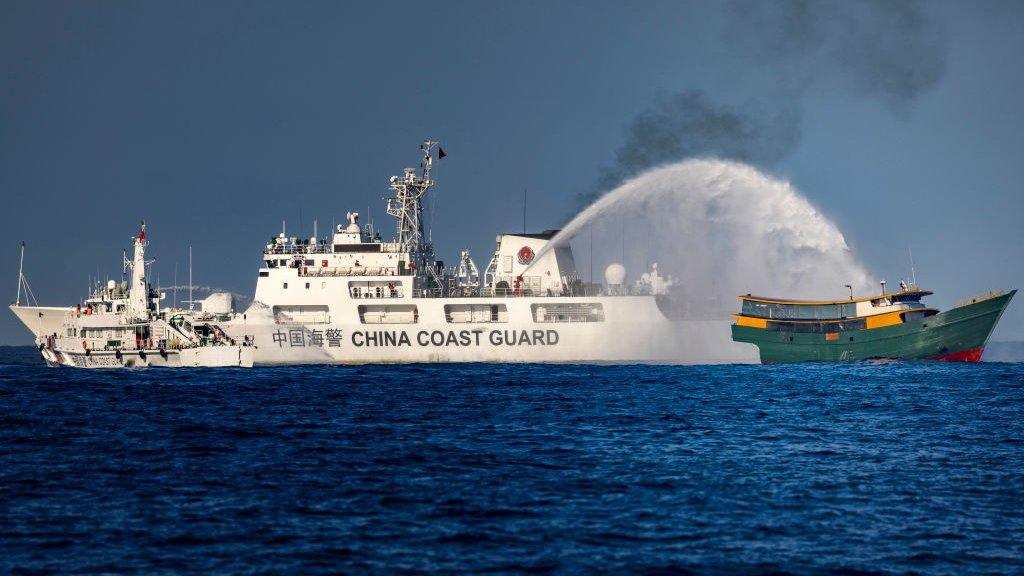 A China coast guard ship fires a water cannon at a Philippine ship in the South China Sea