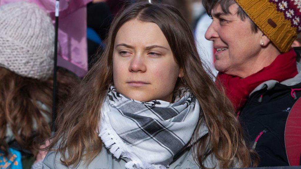 Greta Thunberg at a protest wearing a white and grey scarf