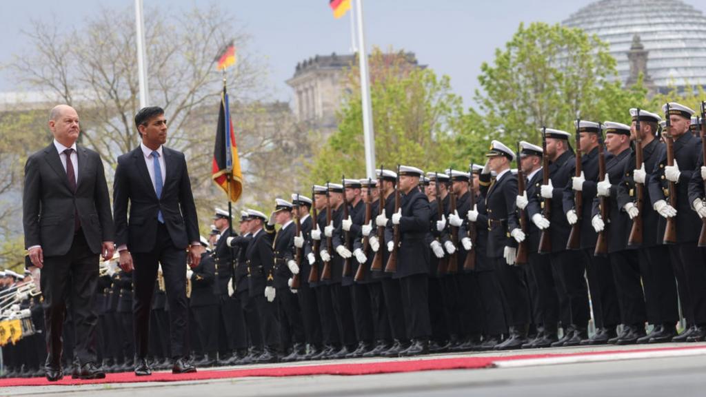 Olaf Scholz and Rishi Sunak walk past a line of soldiers