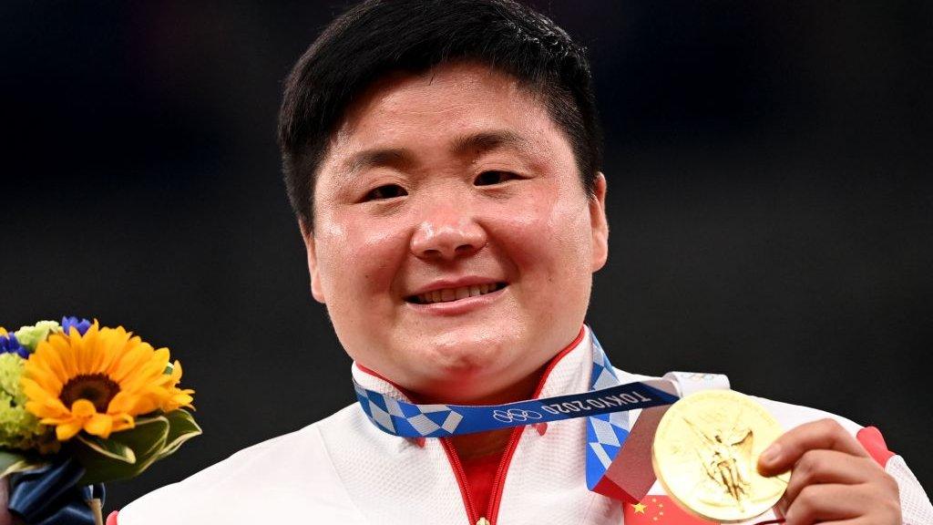 China's Gong Lijiao celebrates on the podium with her gold medal after wining the women's shot put event during the Tokyo 2020 Olympic Games at the Olympic Stadium in Tokyo on 1 August 2021.