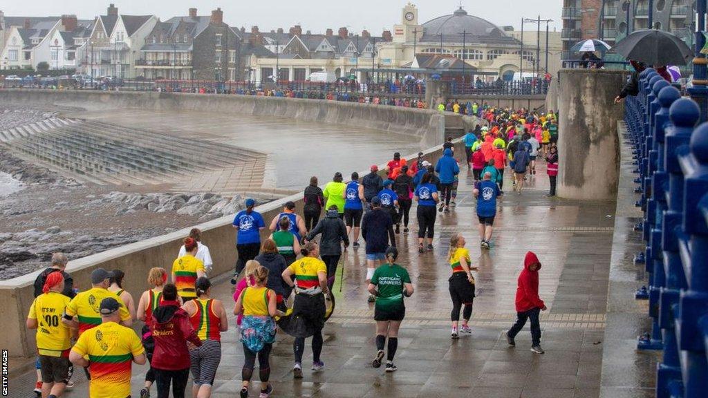 Parkrun participants run along an esplanade