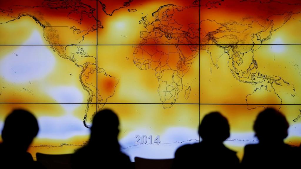 : Participants are seen in silhouette as they look at a screen showing a world map with climate anomalies during the World Climate Change Conference 2015