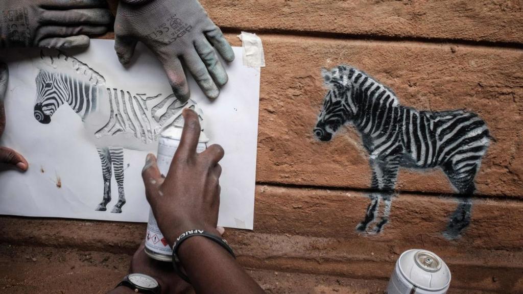 People stencil images of zebras in the Kibera neighbourhood of Nairobi, on April 25, 2018.