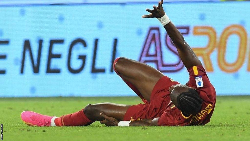 Roma striker Tammy Abraham lies injured on the pitch